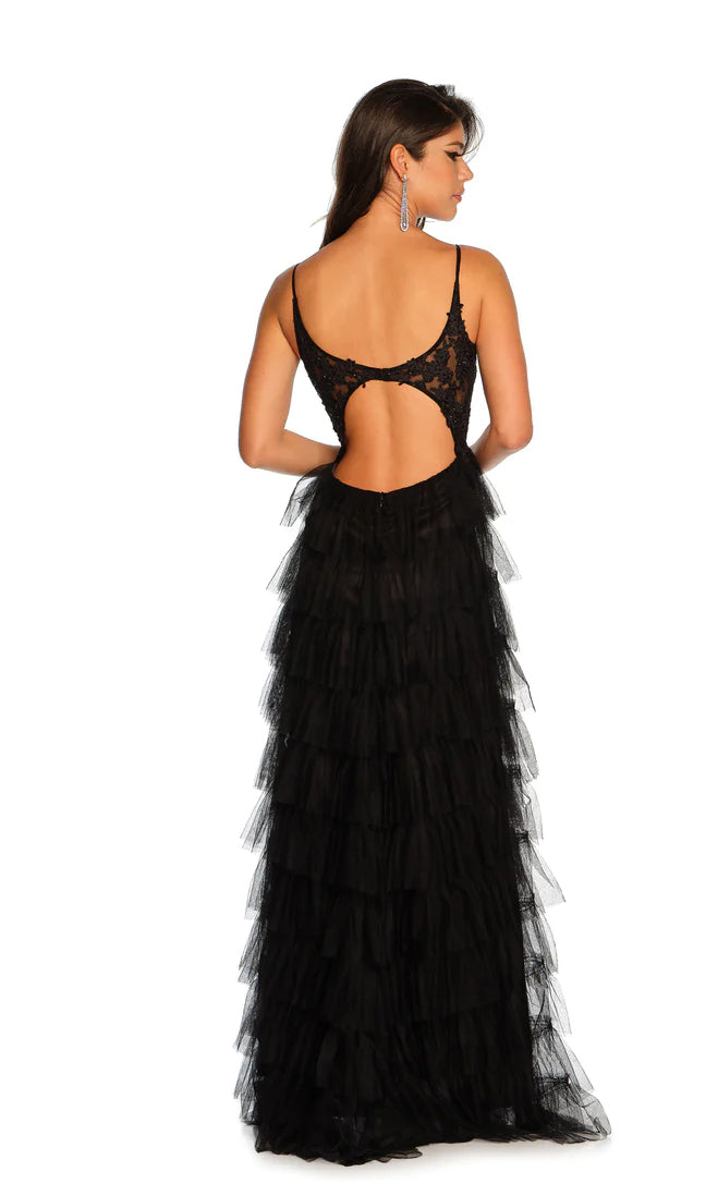 A woman stands facing away, wearing the Dave and Johnny Long Tiered Prom Dress 11148—a formal designer gown with a lace bodice, spaghetti straps, open back, elegant silhouette, and a floor-length tulle skirt.